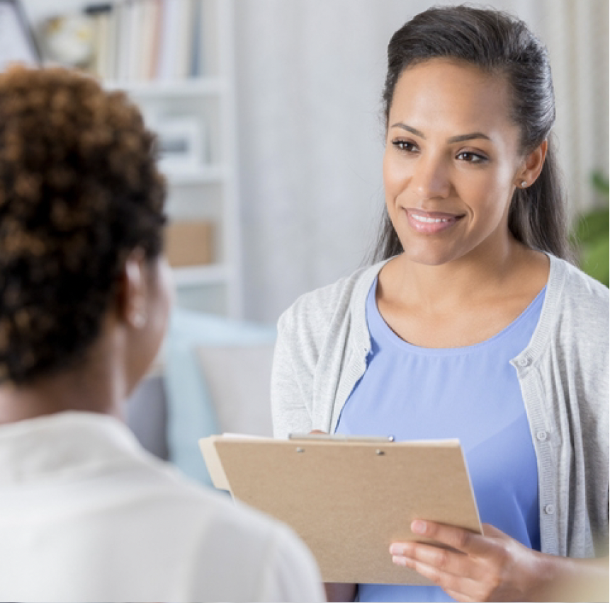 A medical professional with a clipboard talking to another person